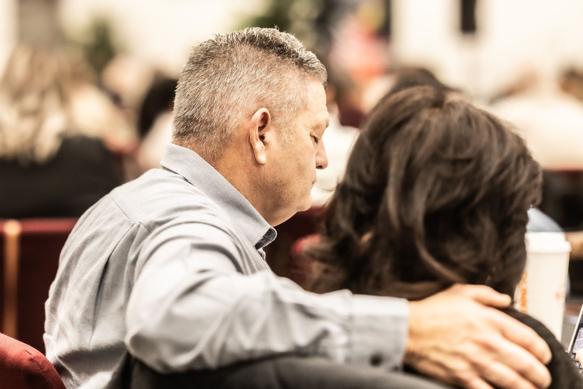 A man is hugging a woman in a crowded room.