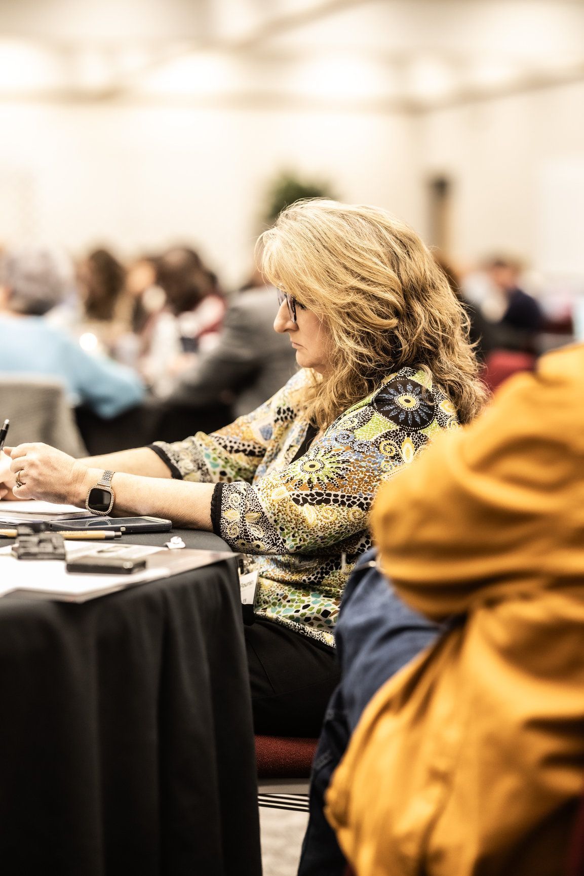 A woman is sitting at a table in a conference room.