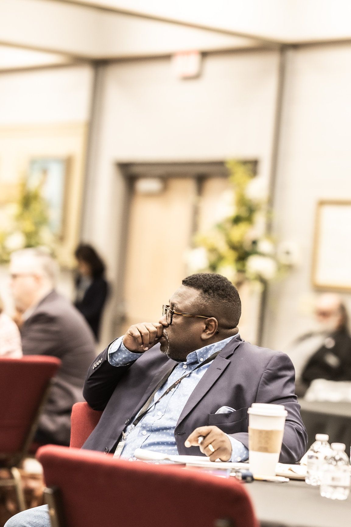 A man in a suit is sitting in a chair with a cup of coffee.