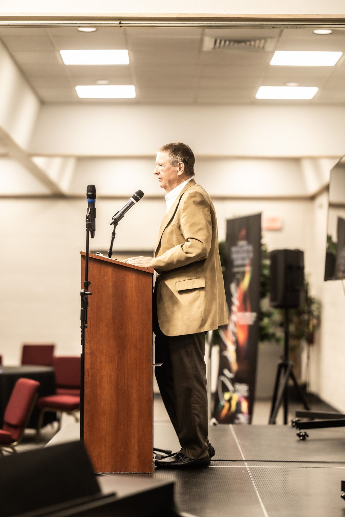 A man is standing at a podium speaking into a microphone.