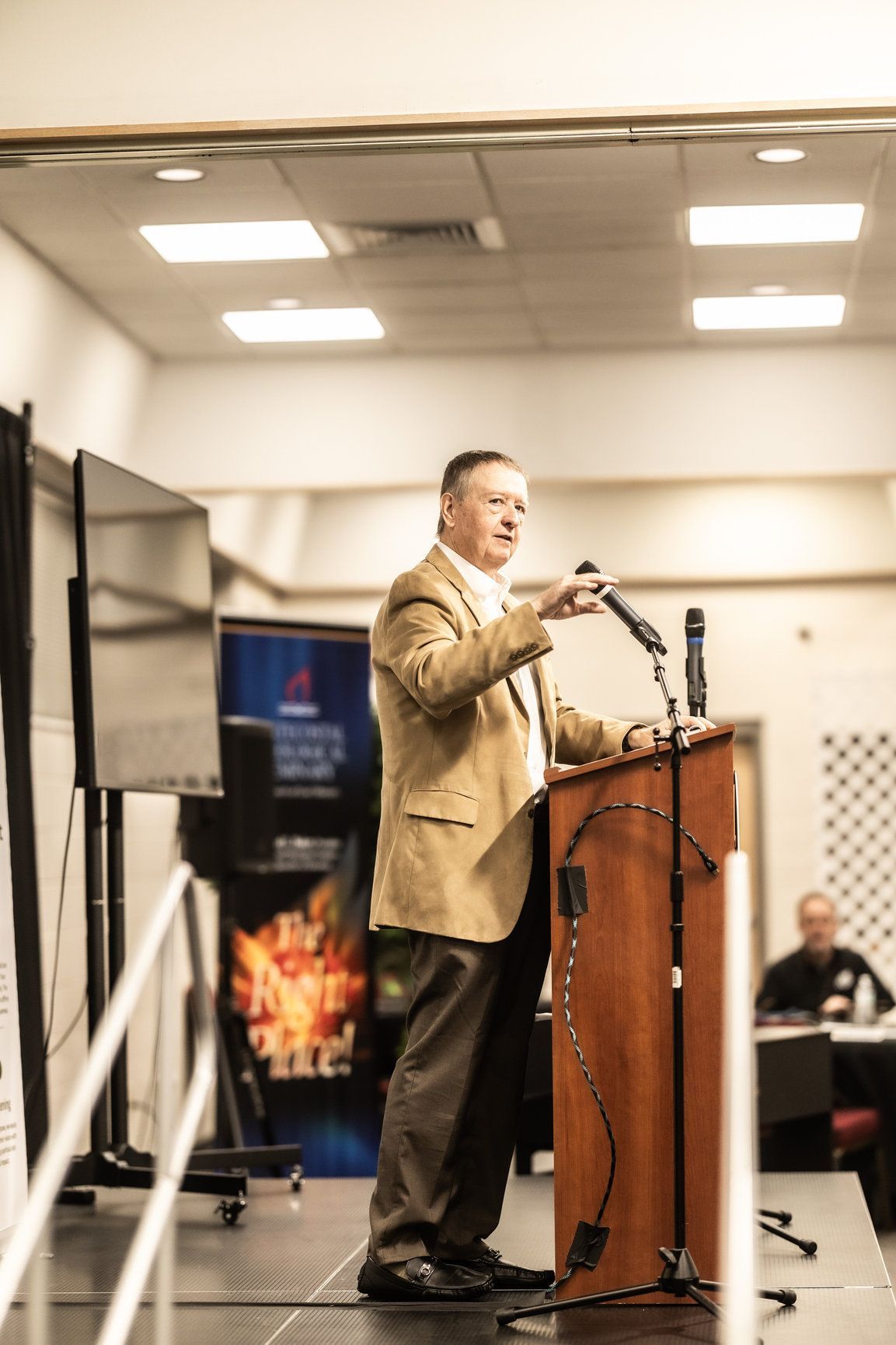 A man is standing at a podium speaking into a microphone.