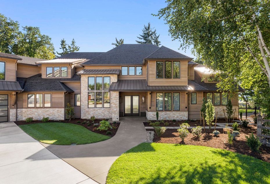 Large two-story brick house with a curved driveway, green lawn, and trees in front