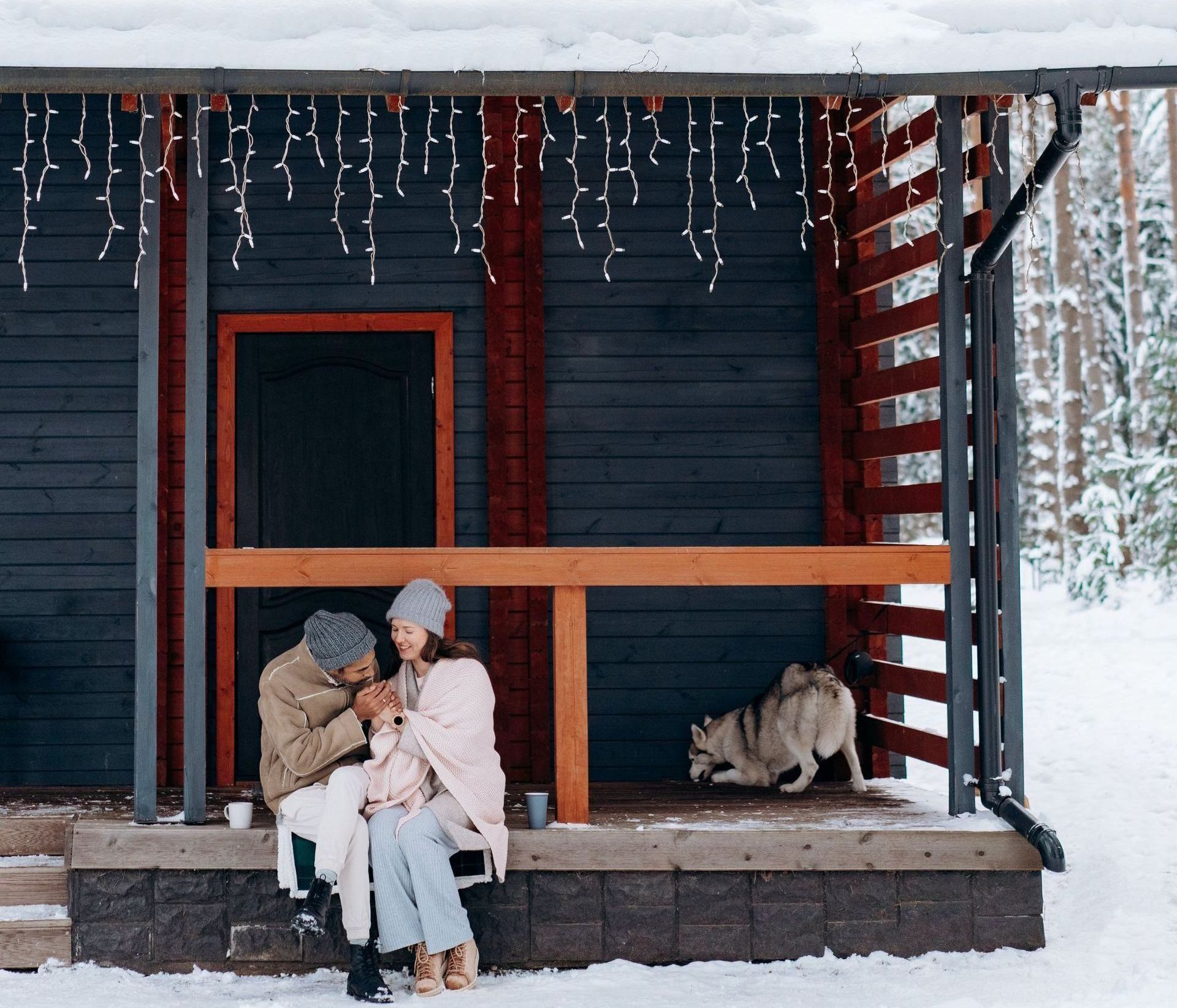 a man and a woman are sitting on a porch with a dog .