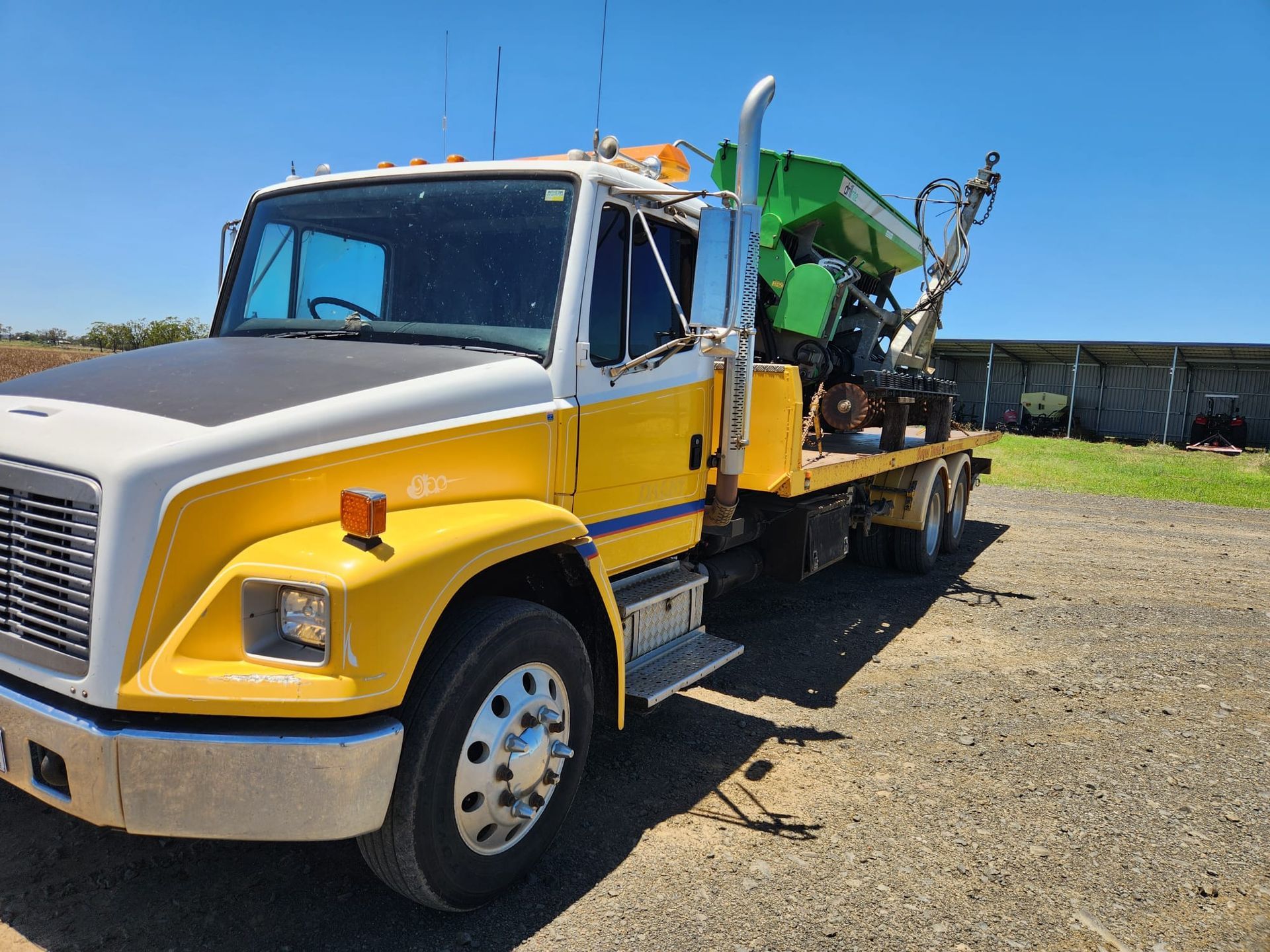 Yellow Tow Truck Next To A Red Car In A Field. Overcast Sky — Downs Towing & Recovery Service in Dalby, QLD