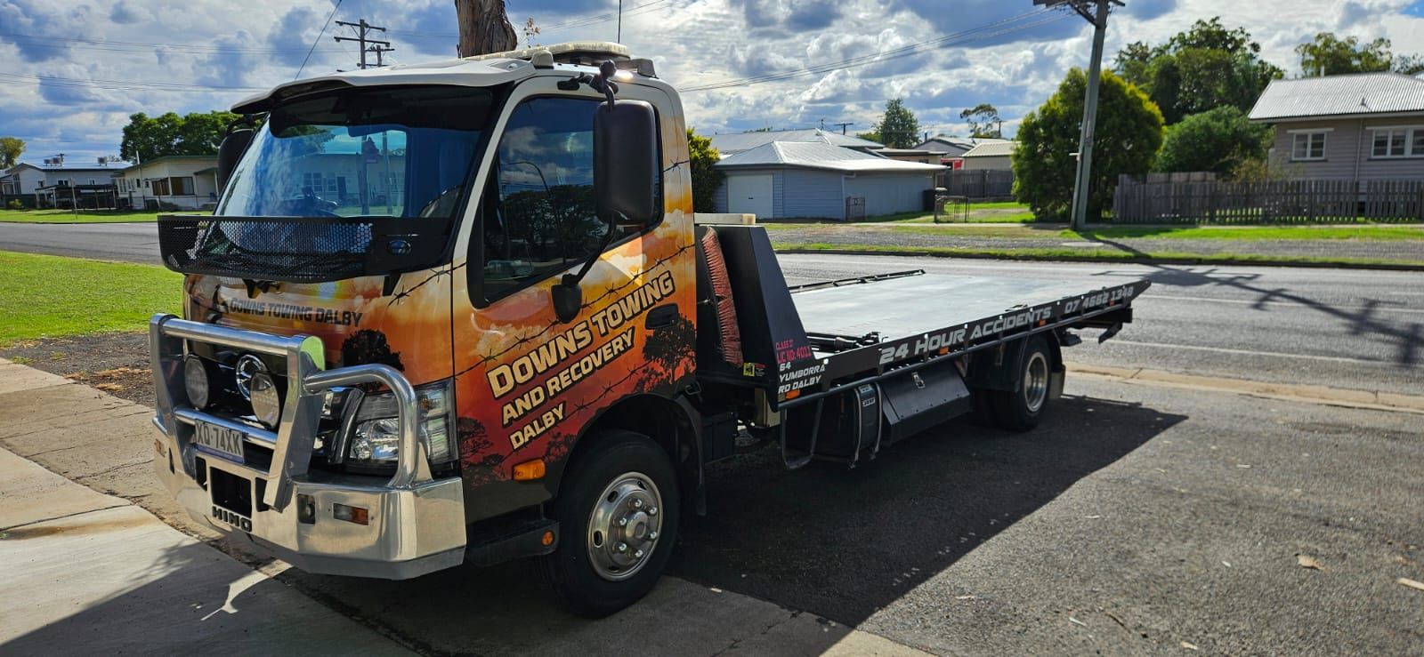 Tow truck with orange flame graphics parked on a street under a cloudy sky — Downs Towing & Recovery Service in St. George, QLD
