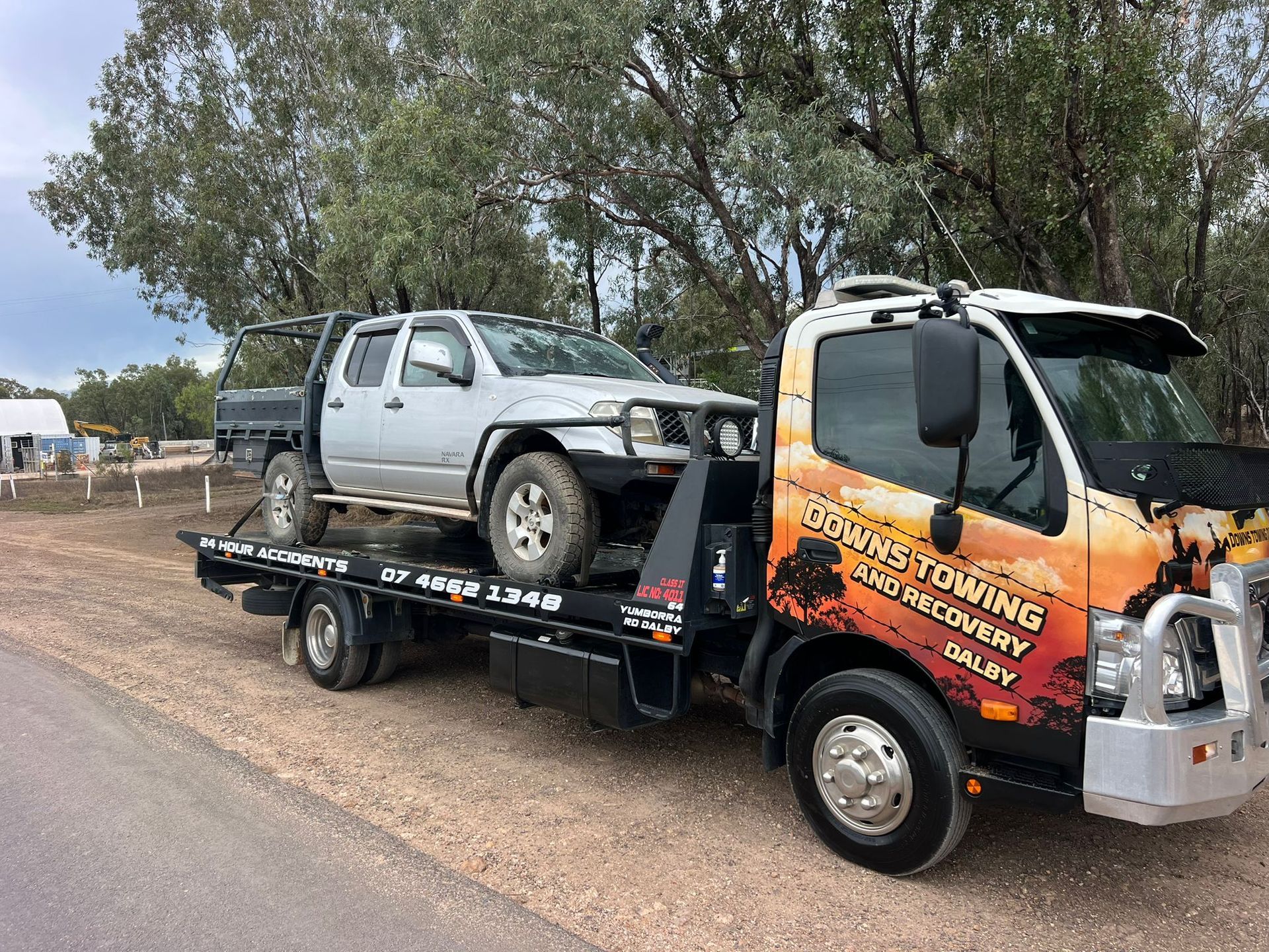 Tow Truck Hauling A Silver Pickup On A Flatbed Beside A Roadside With Trees — Downs Towing & Recovery Service in Miles, QLD
