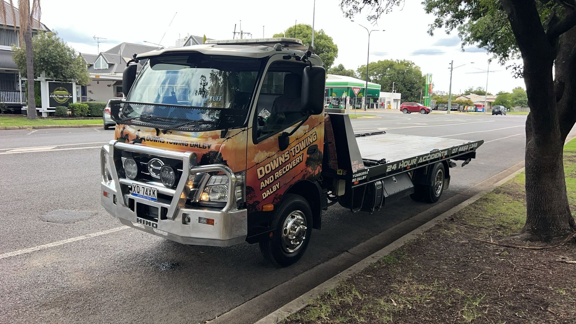 Tow Truck Hauling A Damaged Silver Pickup On A Roadside, With Trees In The Background — Downs Towing & Recovery Service in Moonie, QLD