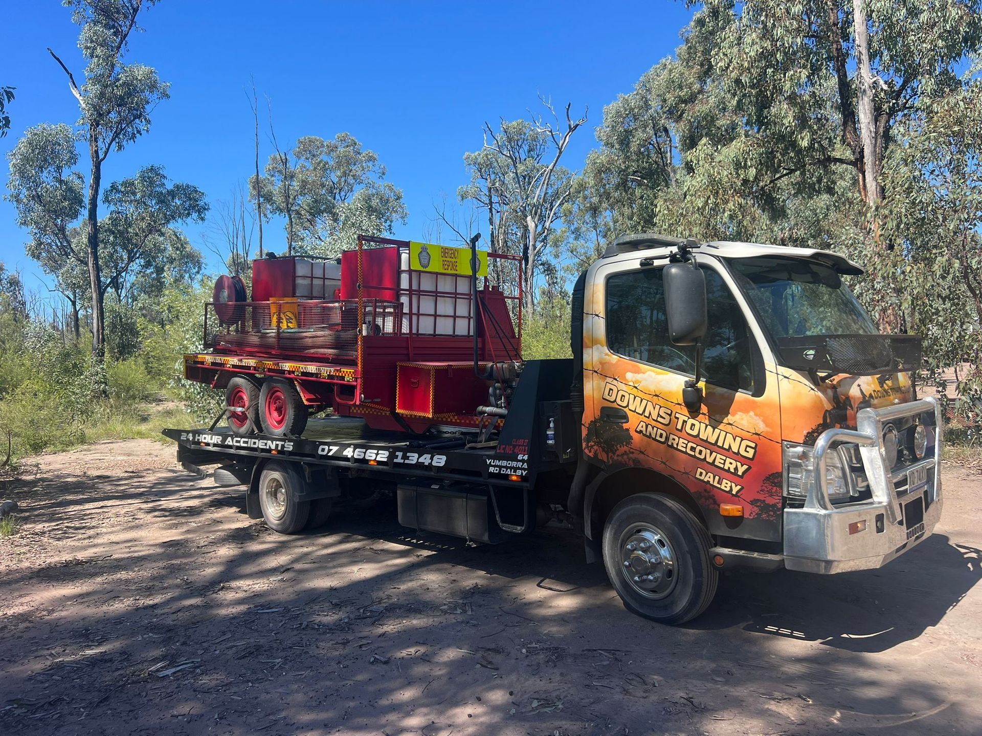 Truck With Red Cargo Bed Parked On A Dirt Road In A Wooded Area Under A Bright Blue Sky — Downs Towing & Recovery Service in Moonie, QLD