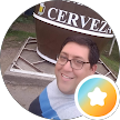 Persona sonriente con gafas junto a un cartel de Cerveza, con una camisa de rayas azules y un icono de una estrella naranja.