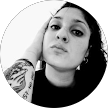 Retrato en blanco y negro en primer plano de una persona con cabello corto y oscuro y un tatuaje en el brazo, mirando a la cámara.