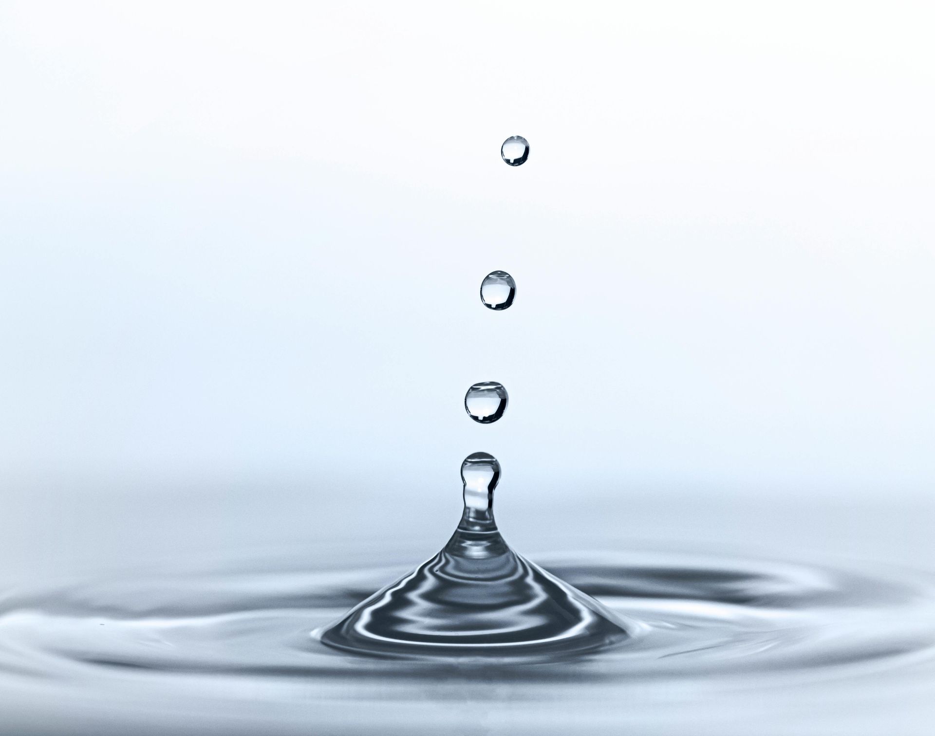 Salpicadura de gotas de agua: tres gotas caen sobre una superficie tranquila, creando ondas.
