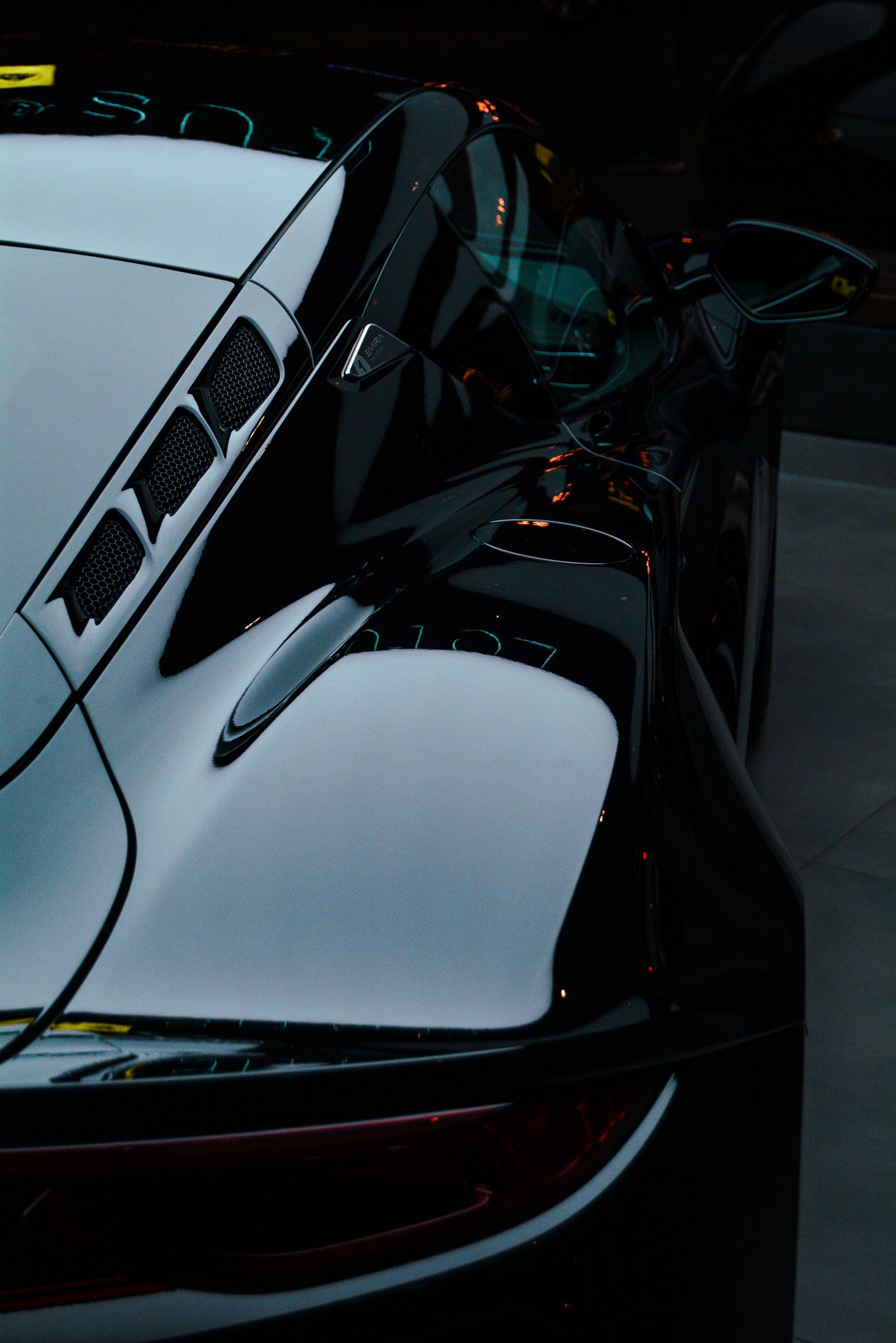 Person applying a yellow cloth to a blue car’s front fender near the headlight