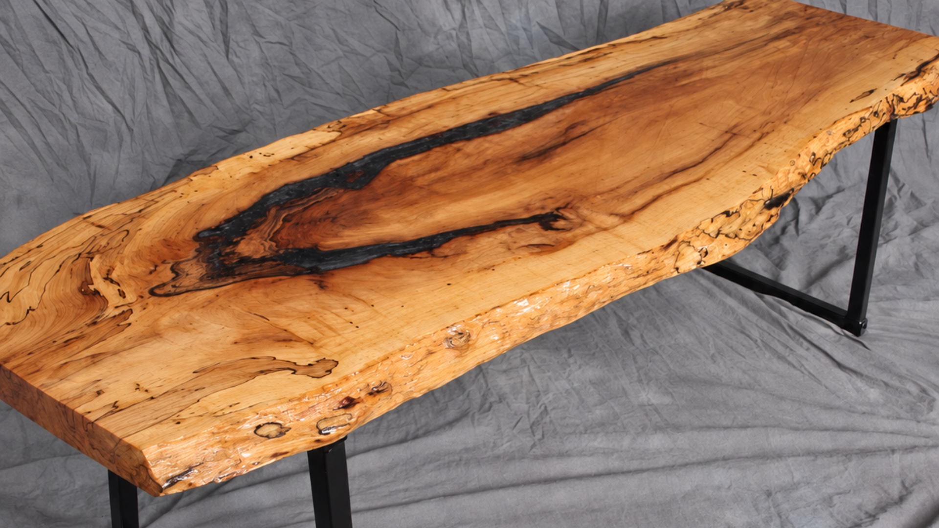 Live-edge wooden table with black metal legs on a gray backdrop,
