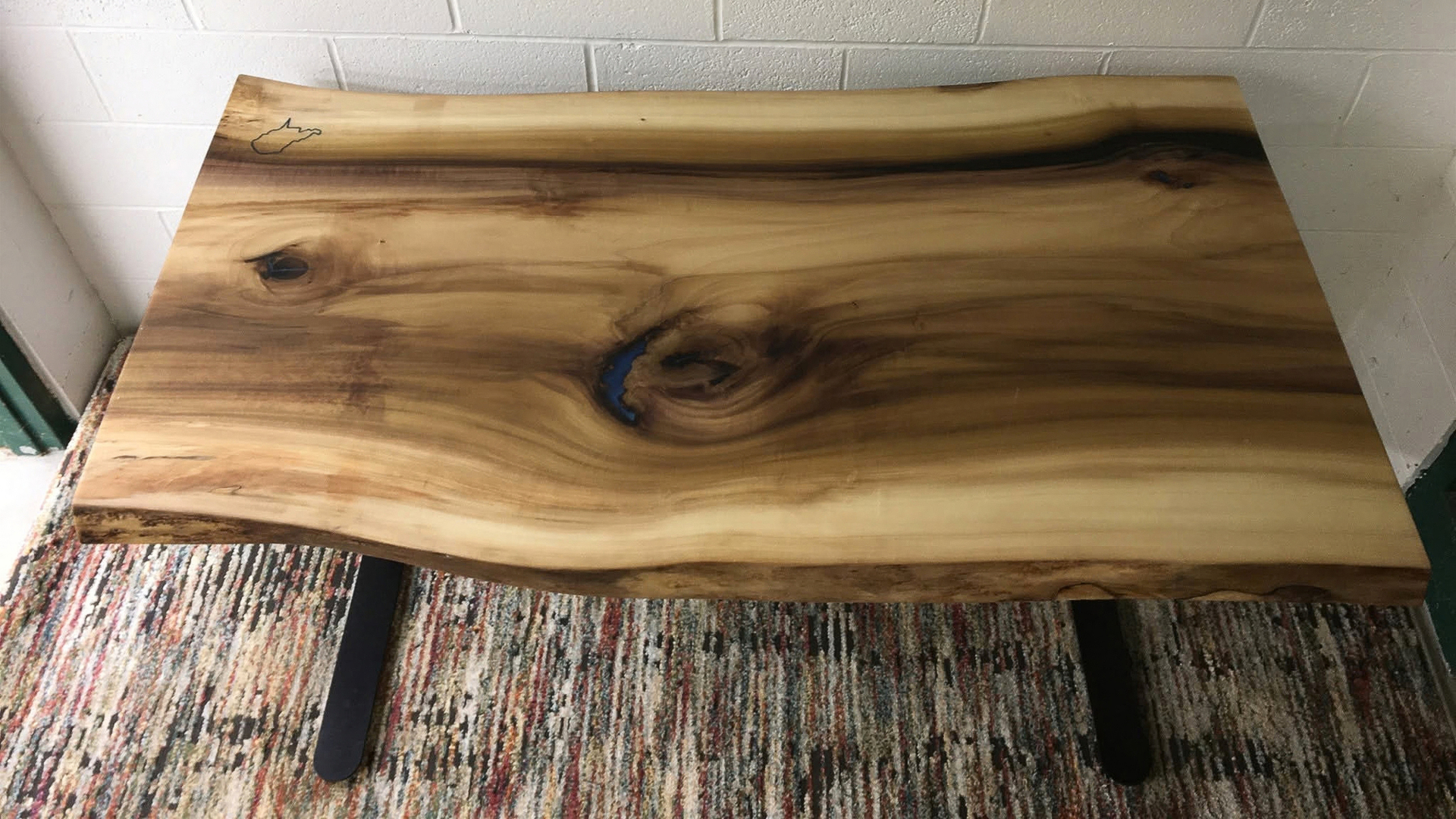 Wood slab tabletop with natural grain and live edge on a patterned rug