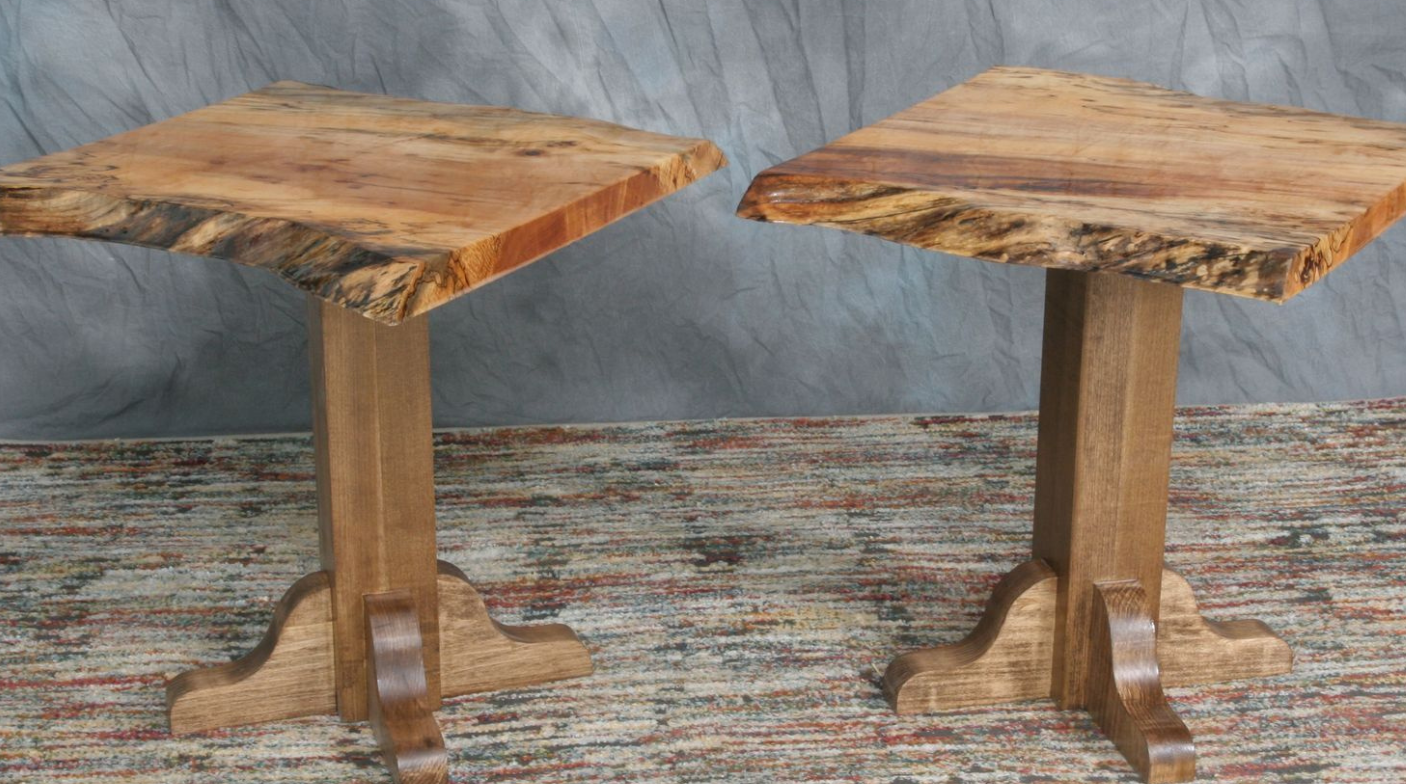 Two rustic wooden pedestal tables with square tops on a patterned rug