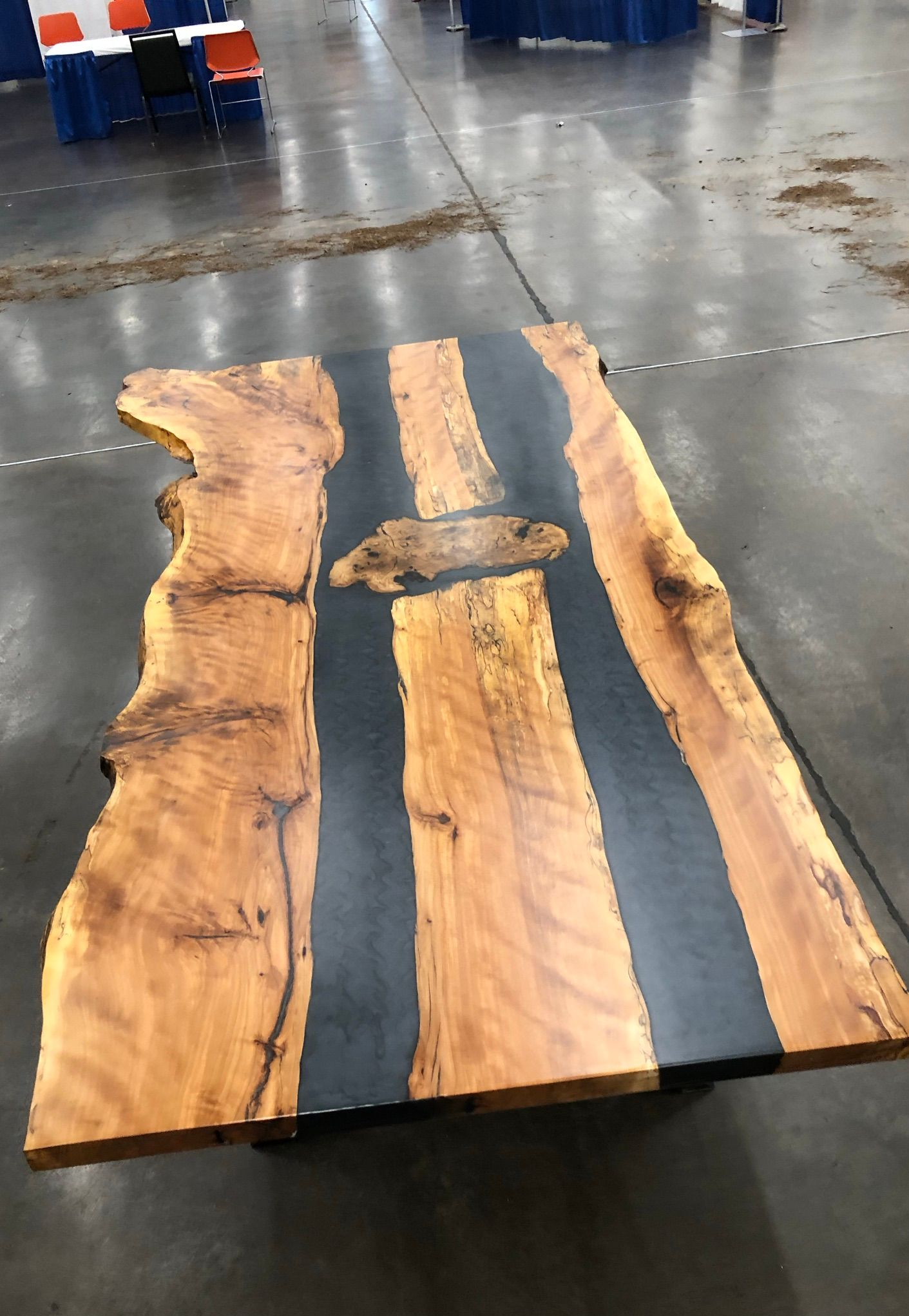 Wooden slab with dark resin stripes on a concrete floor in an indoor workshop.