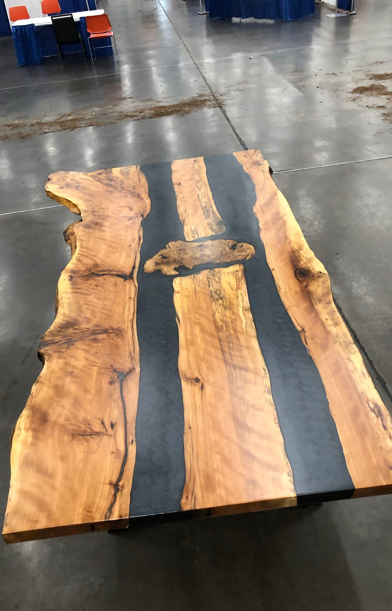 Wooden slab with dark resin stripes on a concrete floor in an indoor workshop.