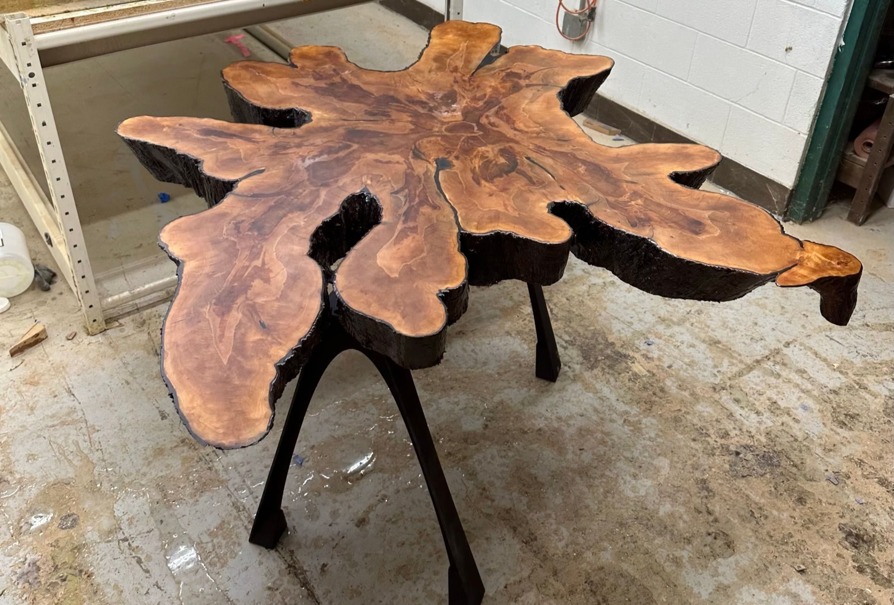 Rustic wood slab table with black metal legs in a workshop setting