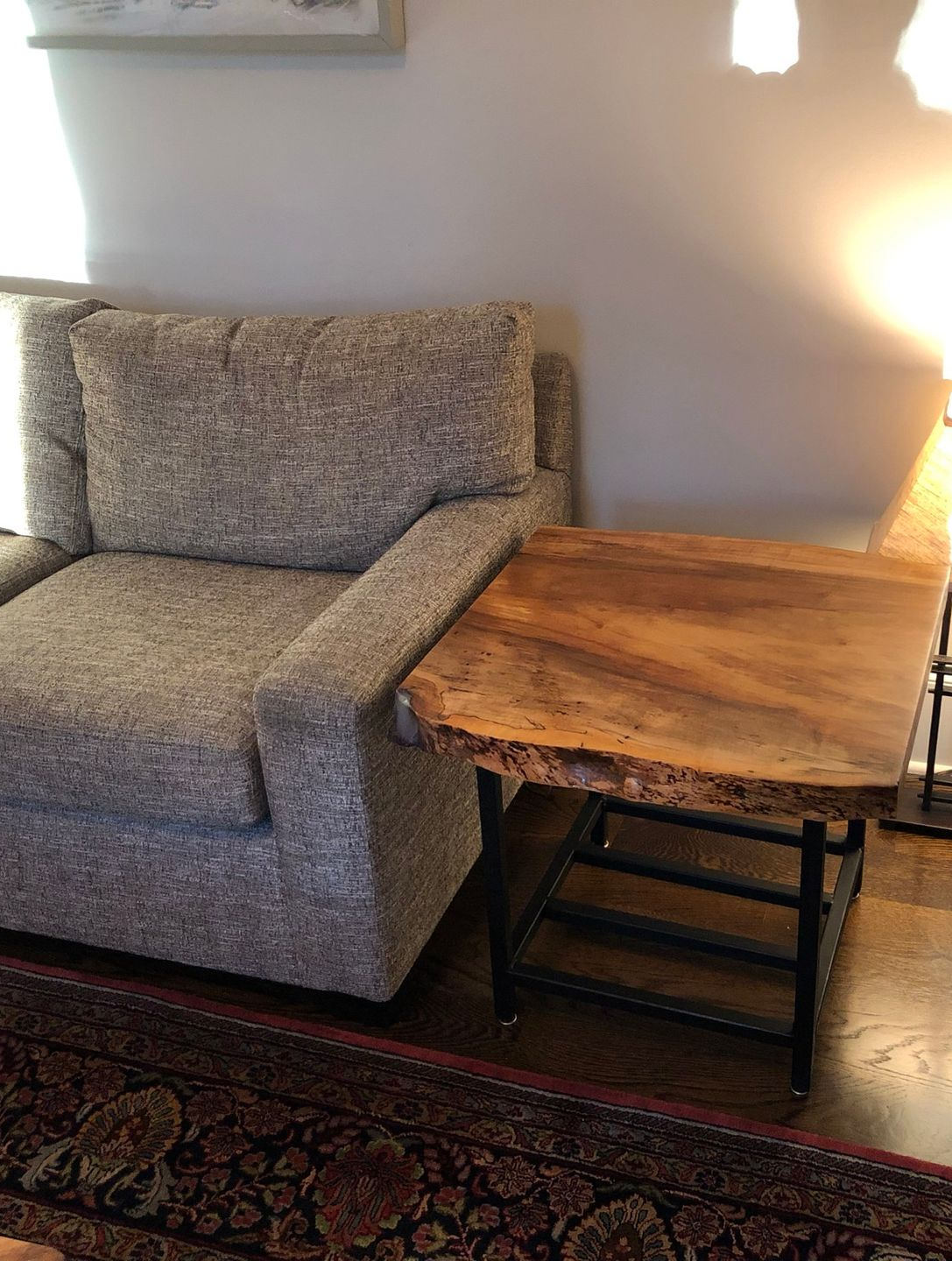 Gray armchair beside a rustic wooden side table in a softly lit living room