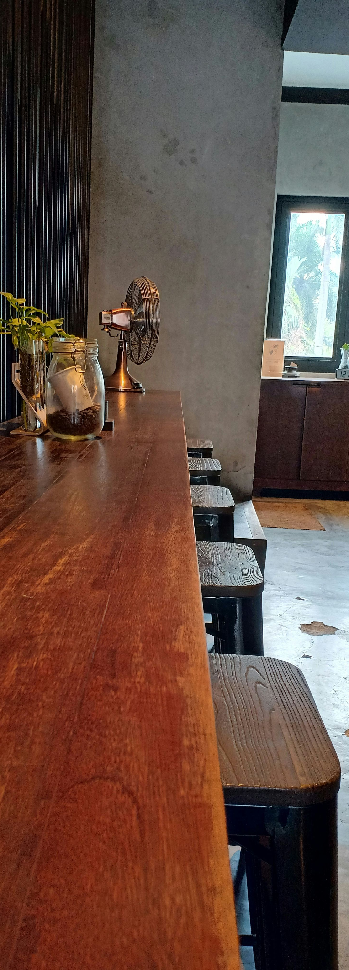 Wooden bar counter beside stools in a softly lit café or restaurant interior.