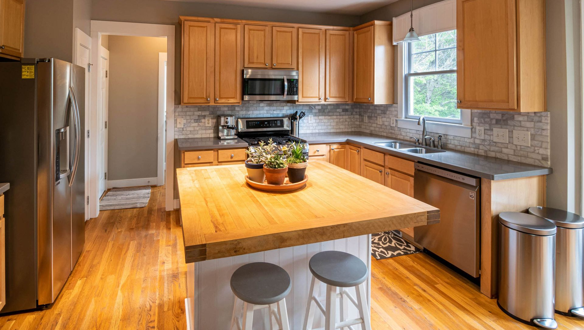 Modern kitchen with wood island, stainless appliances, tan cabinets, and a bowl centerpiece