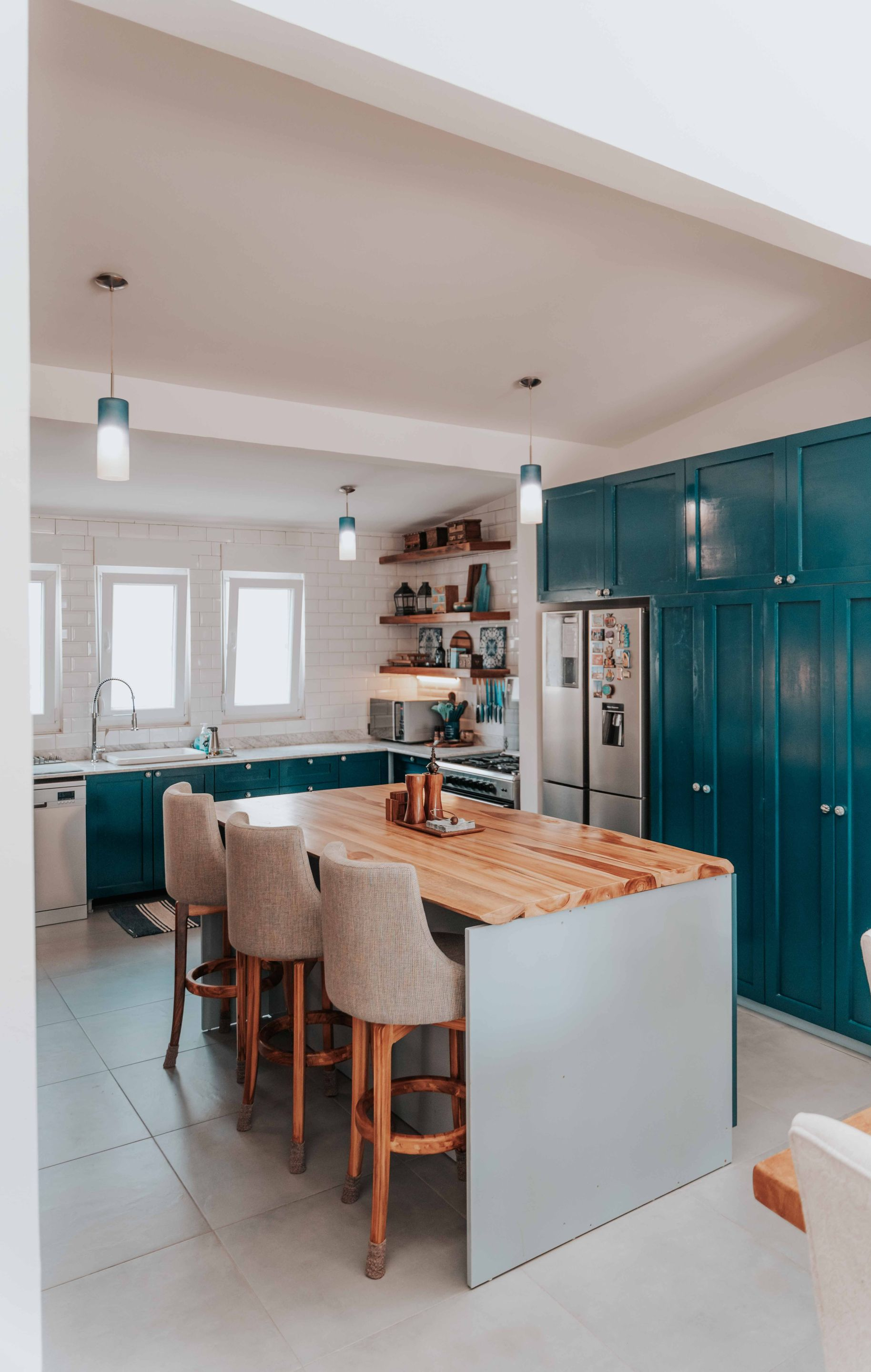 Modern kitchen with teal cabinets, island seating, and wood countertops
