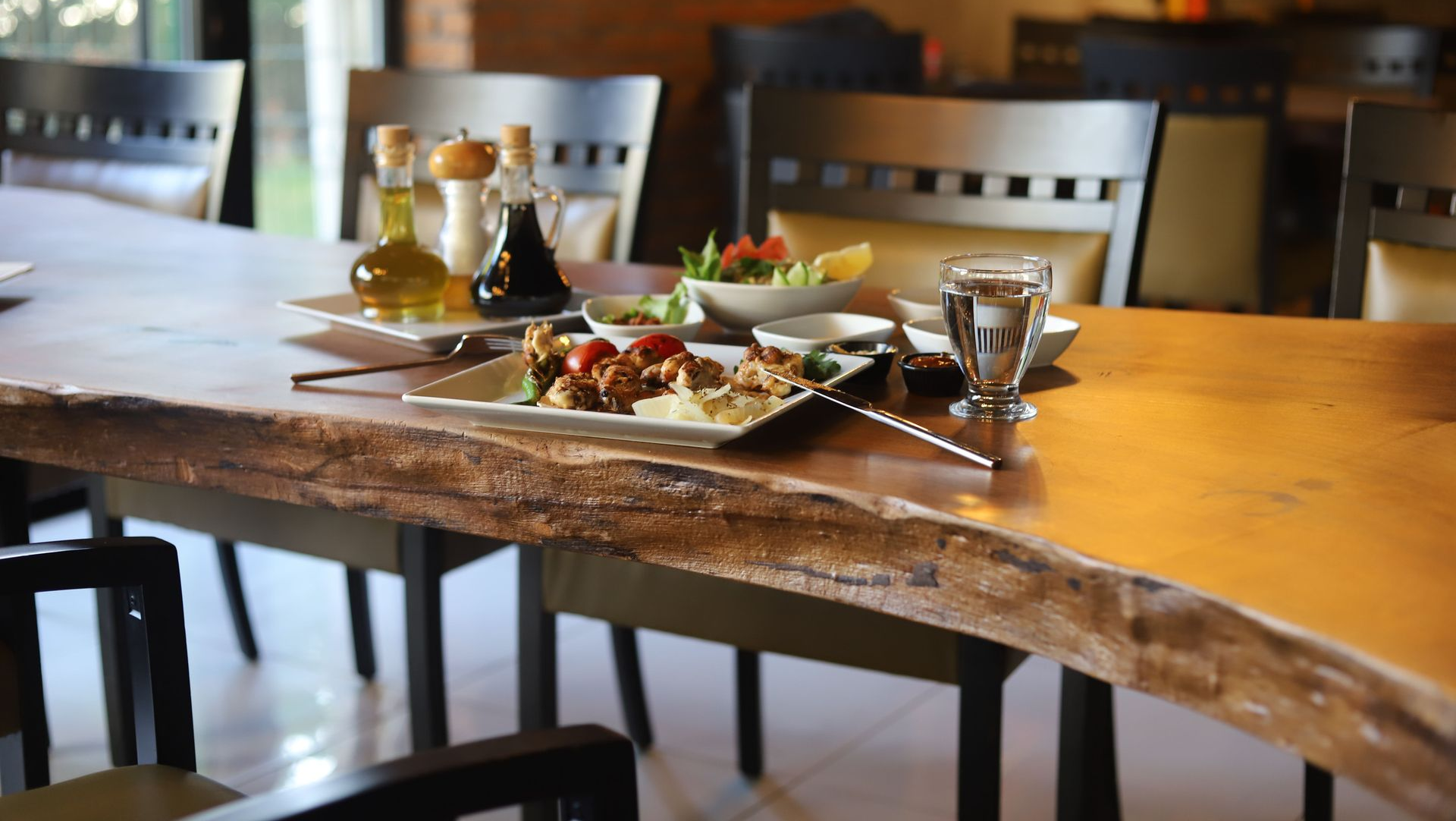 Restaurant table set with plates of food, drinks, and condiments on a wooden table