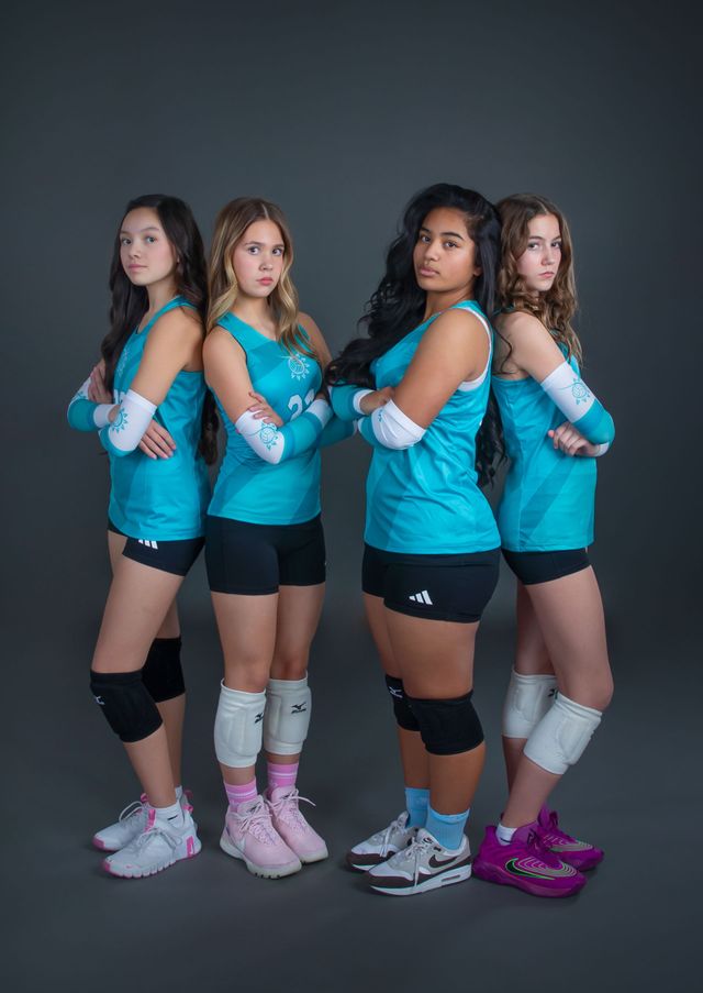 Four volleyball players in teal jerseys pose with crossed arms against a dark studio backdrop.