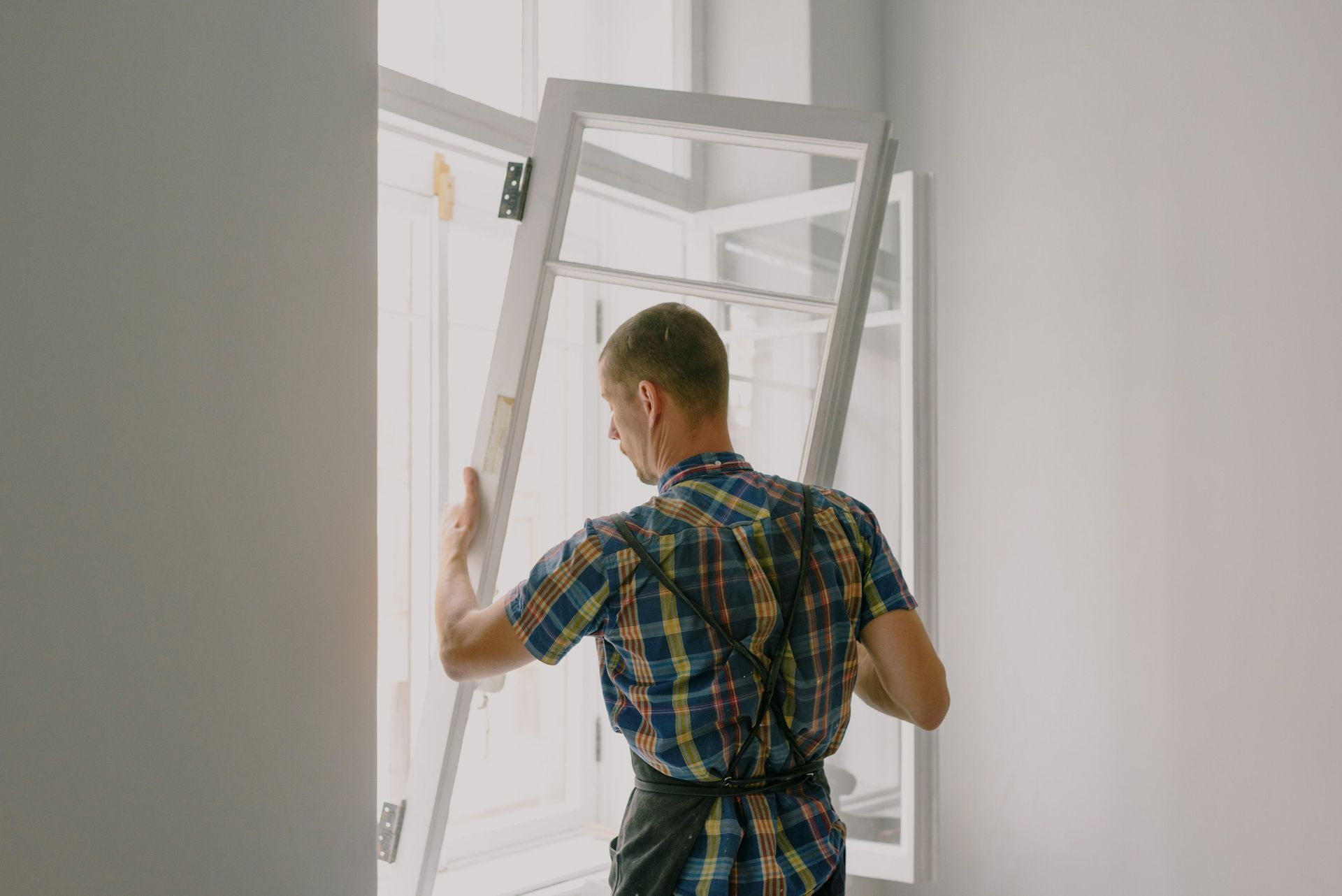 Person carrying a white door through a bright interior doorway
