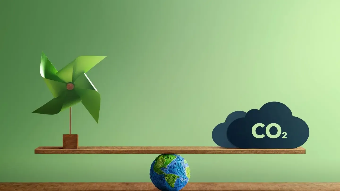 A windmill and a globe are balancing on a wooden scale.