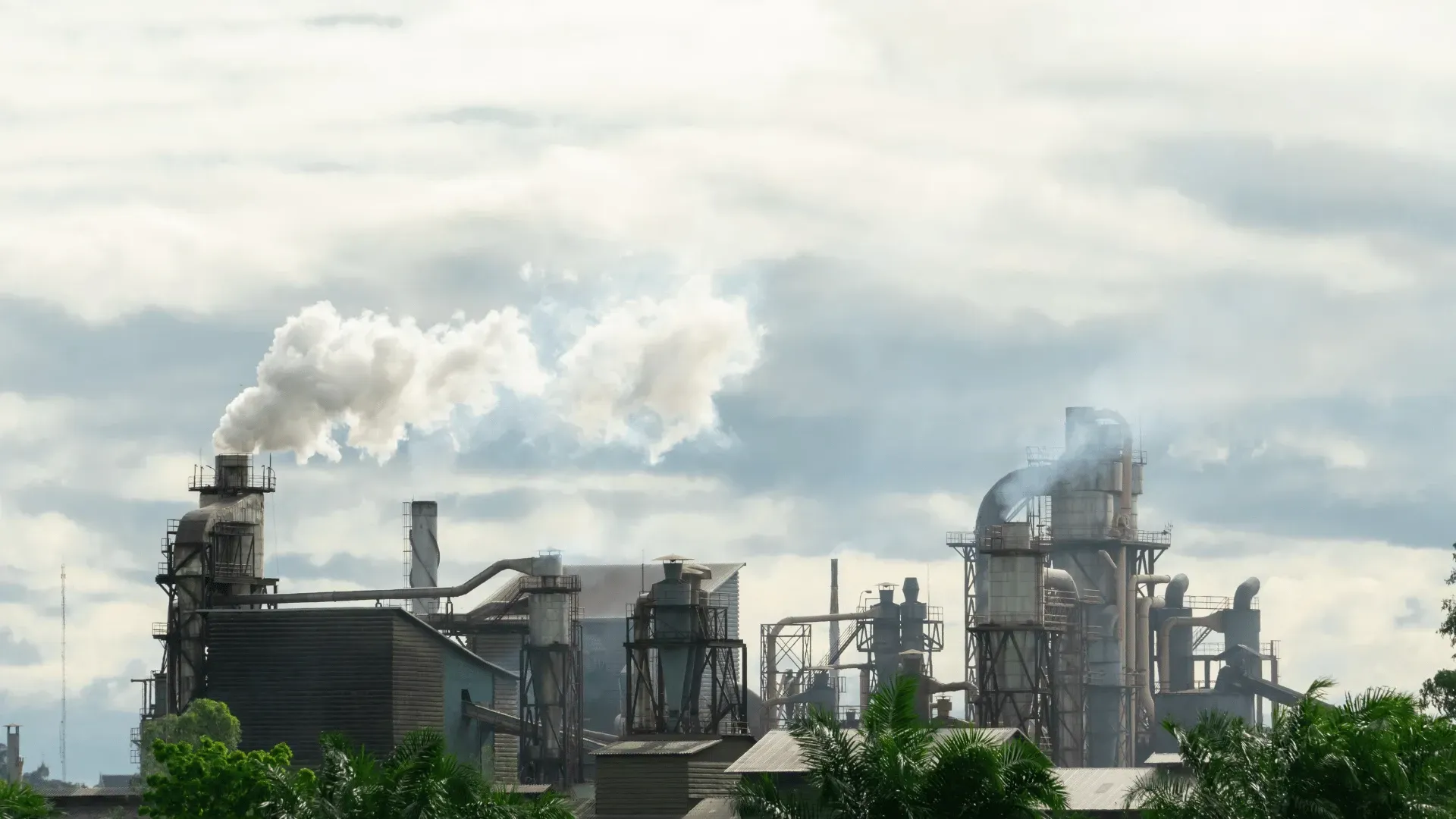 A factory with smoke coming out of the chimneys on a cloudy day.