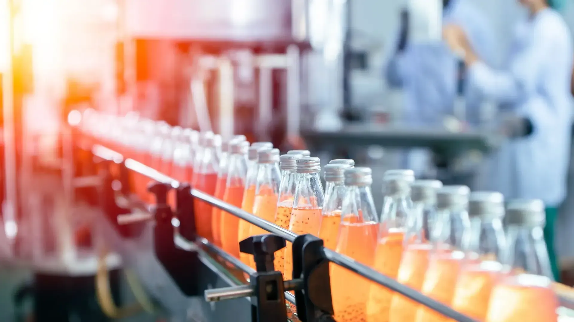 A conveyor belt filled with bottles of soda in a factory.