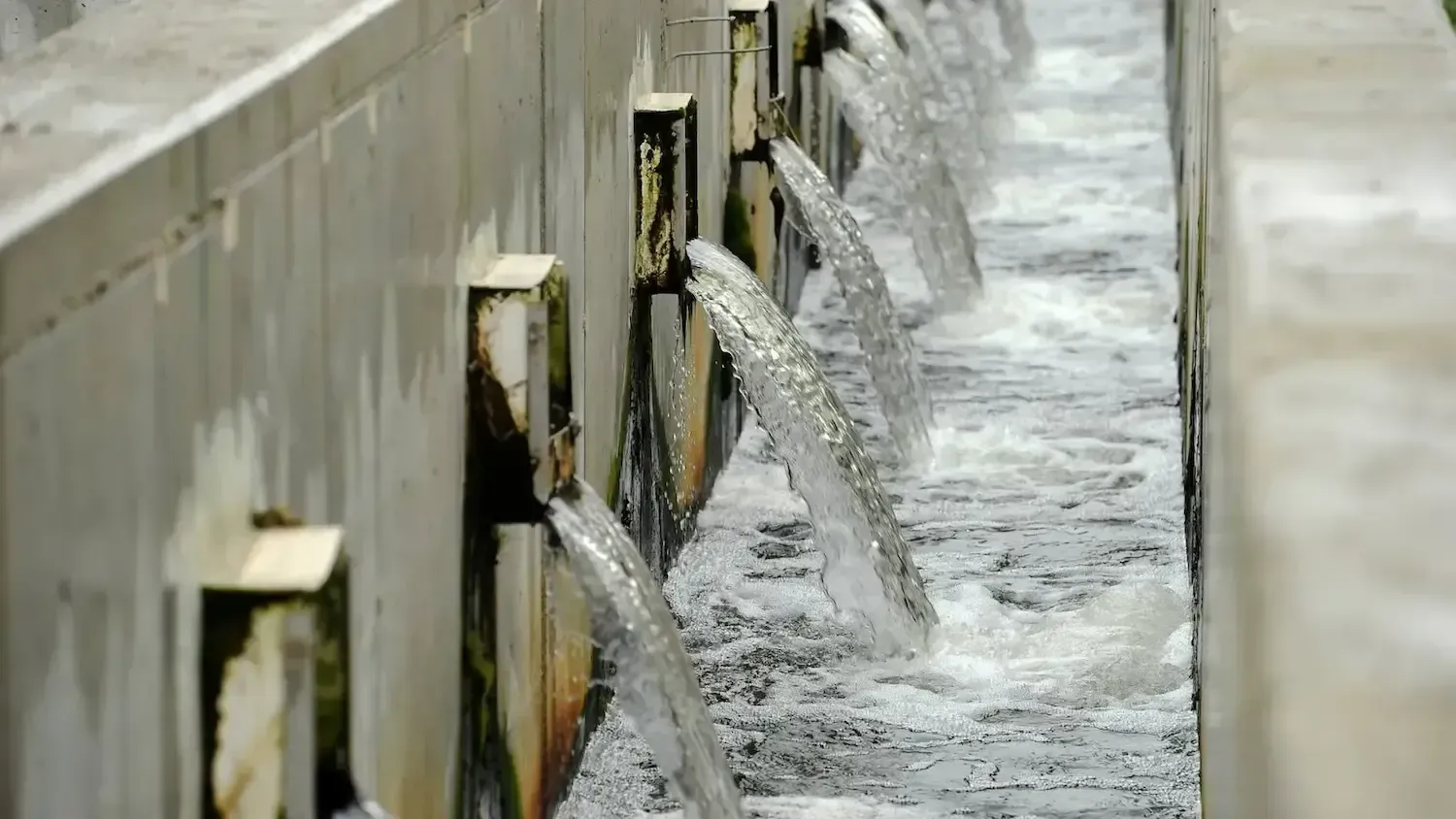 A stream of water is flowing through a concrete wall.
