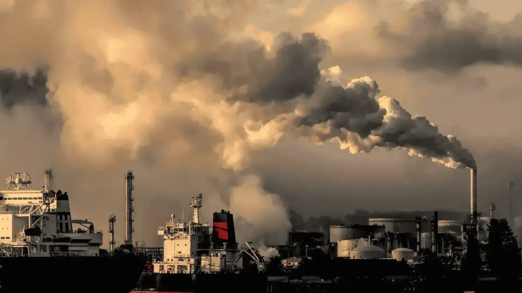 Smoke is coming out of a factory with a cloudy sky in the background.
