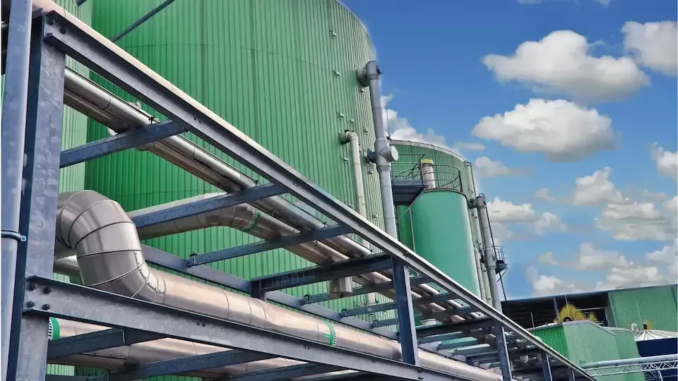 A green building with pipes going through it and a blue sky in the background.