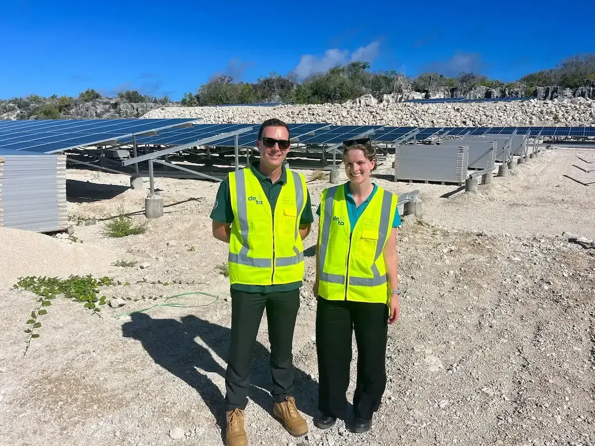 A man and a woman are standing in front of a solar panel field.