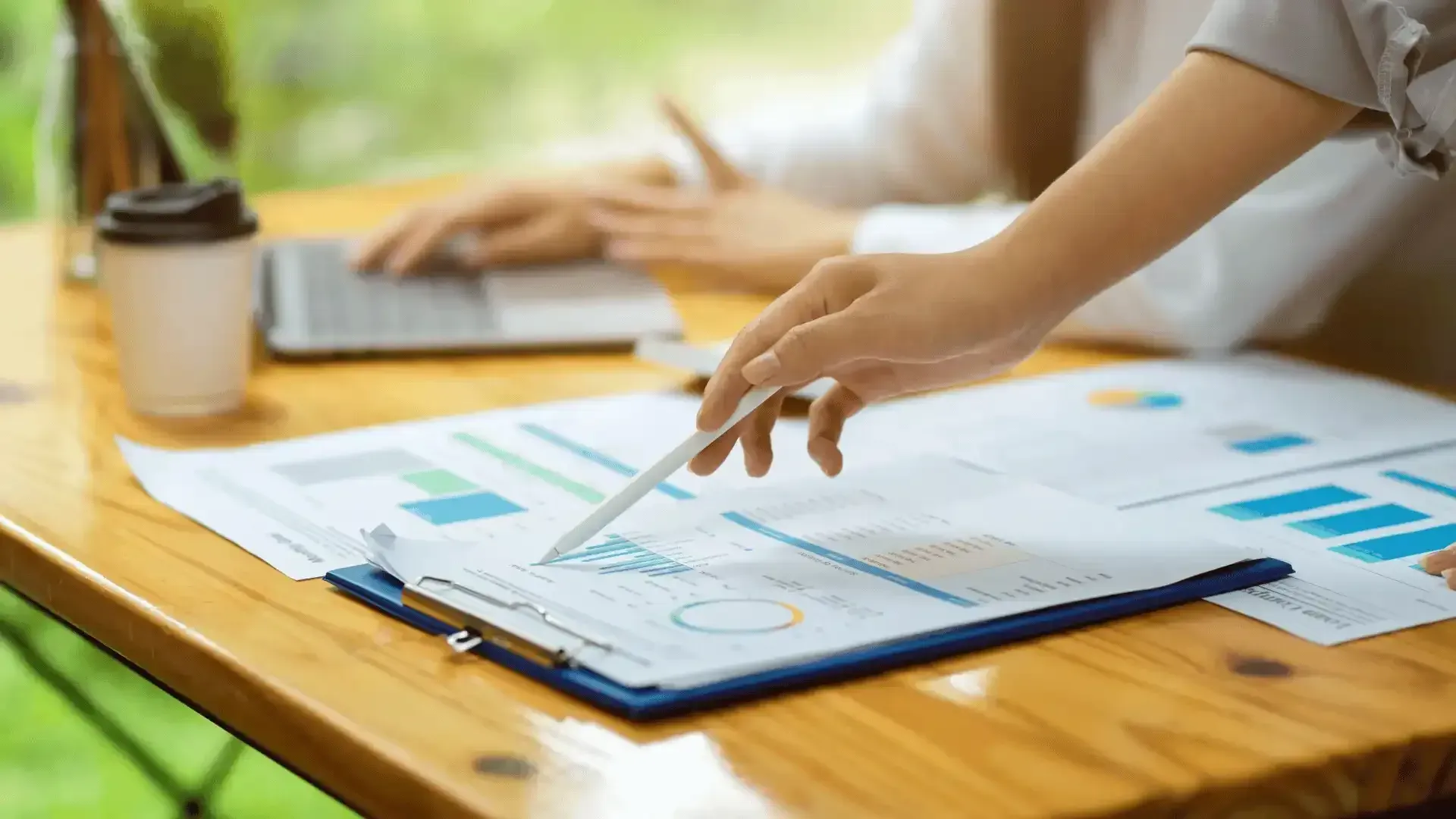 A person is pointing at a graph on a clipboard with a pen.