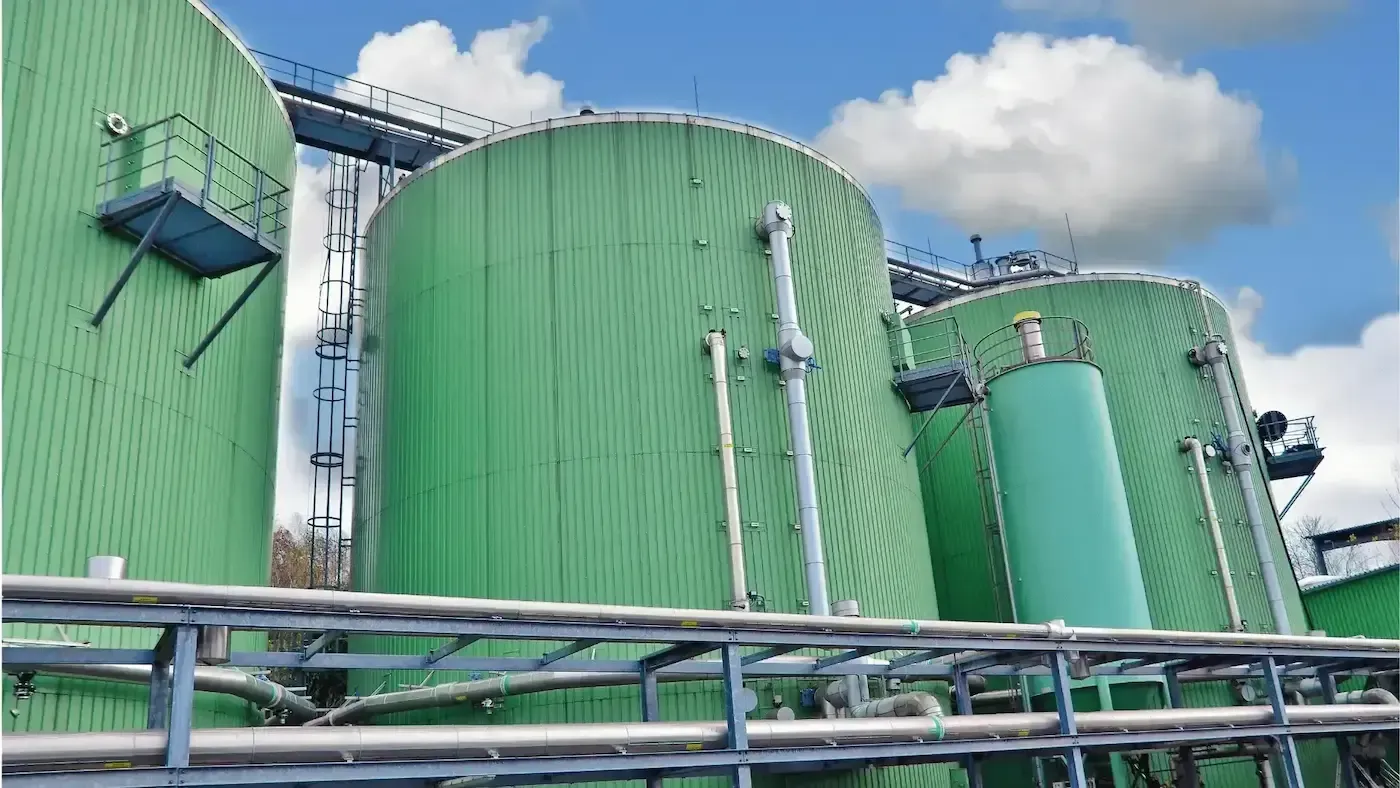 A row of green tanks are sitting next to each other in a factory.