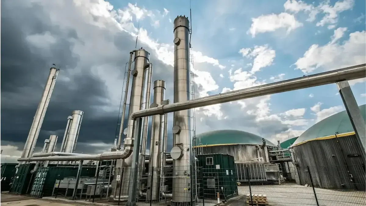 A factory with a lot of pipes and a cloudy sky in the background.