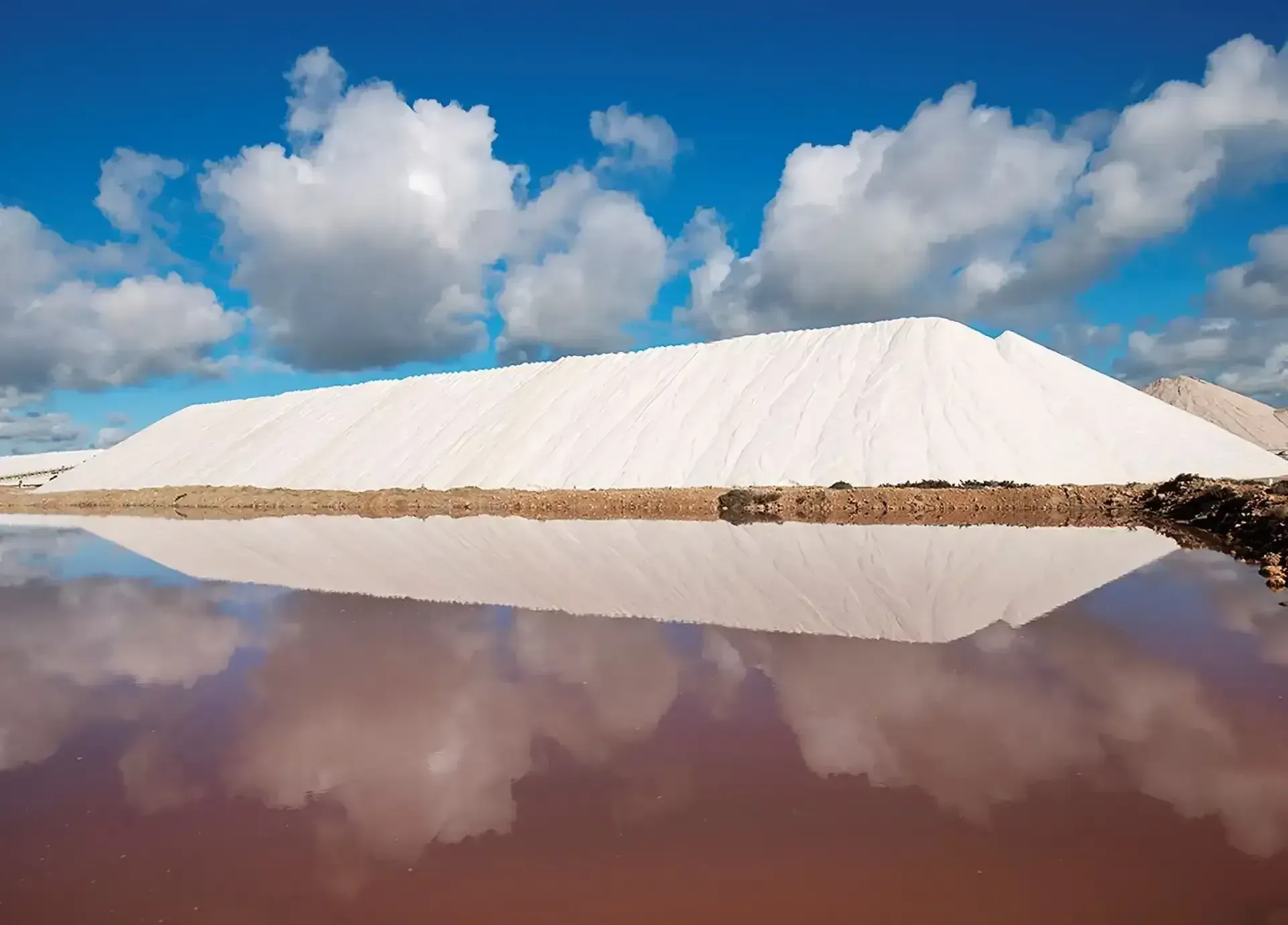 A large white hill is reflected in a body of water