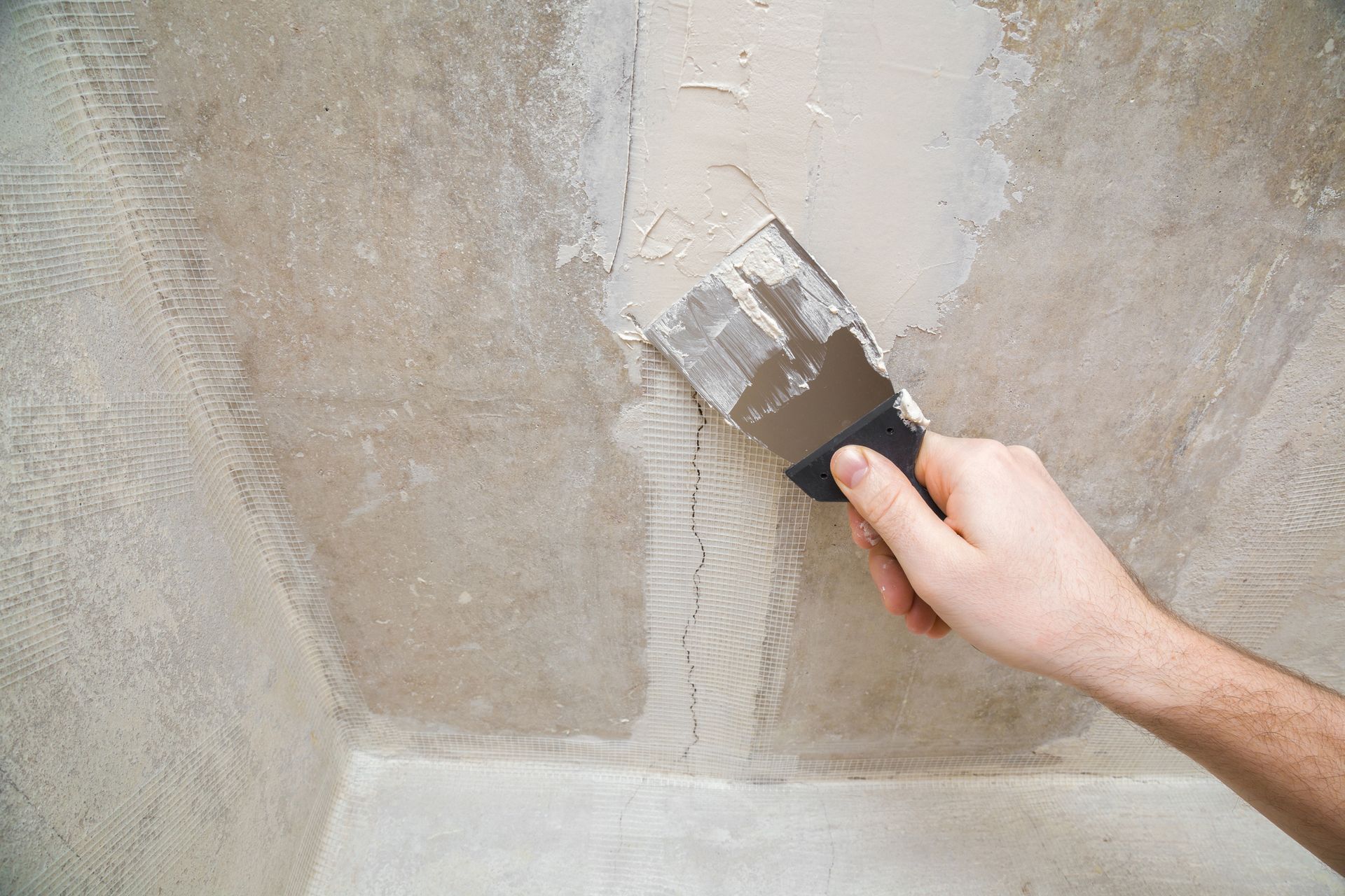 A person is plastering a wall with a spatula.