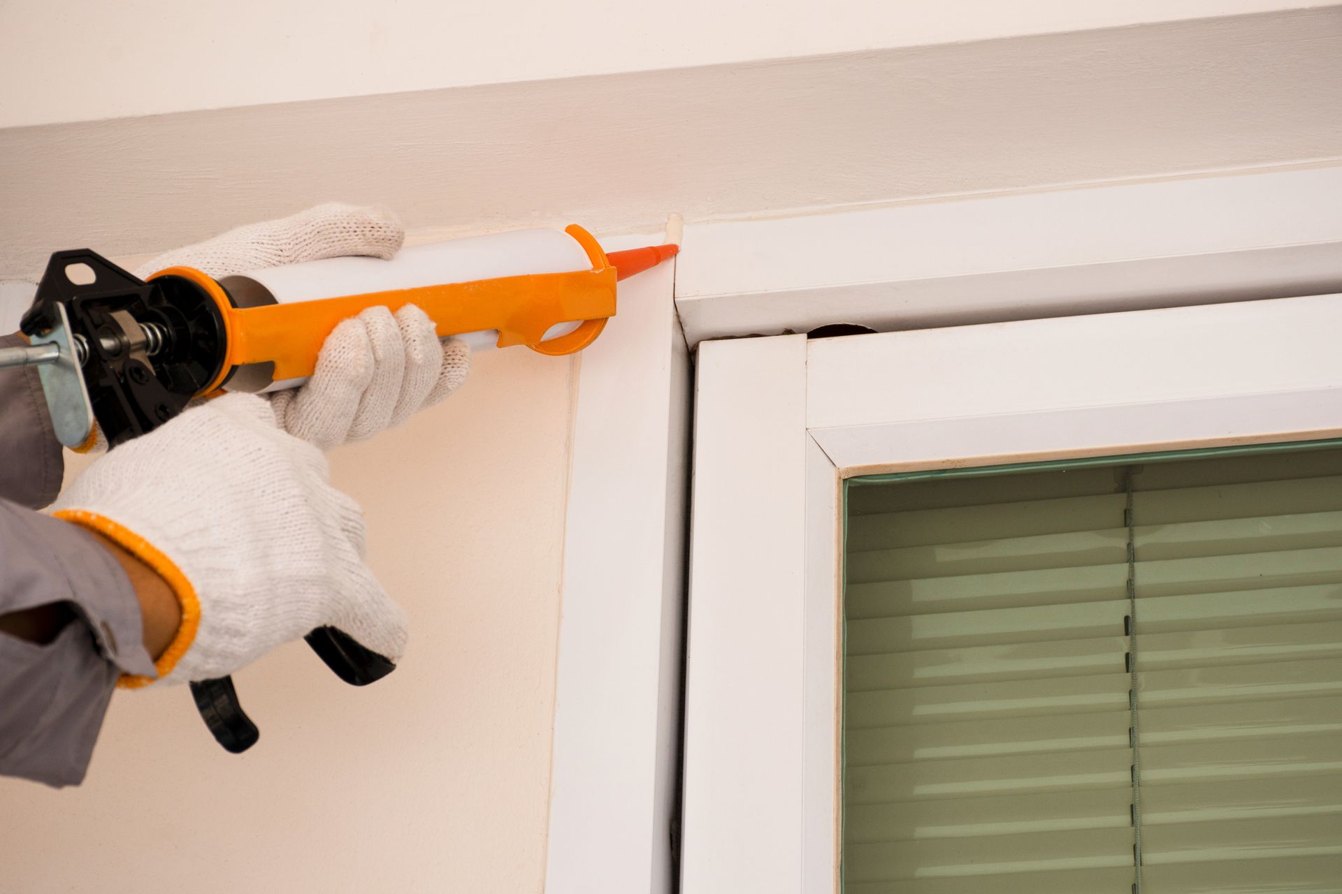 A person is applying sealant to a window frame.
