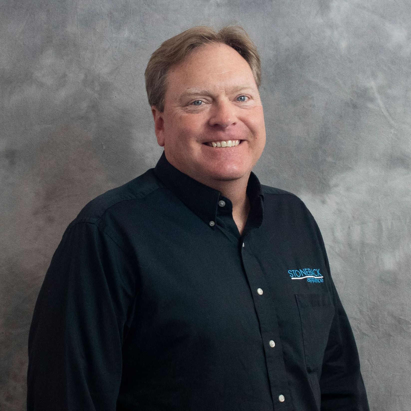 A man in a black shirt is smiling for the camera