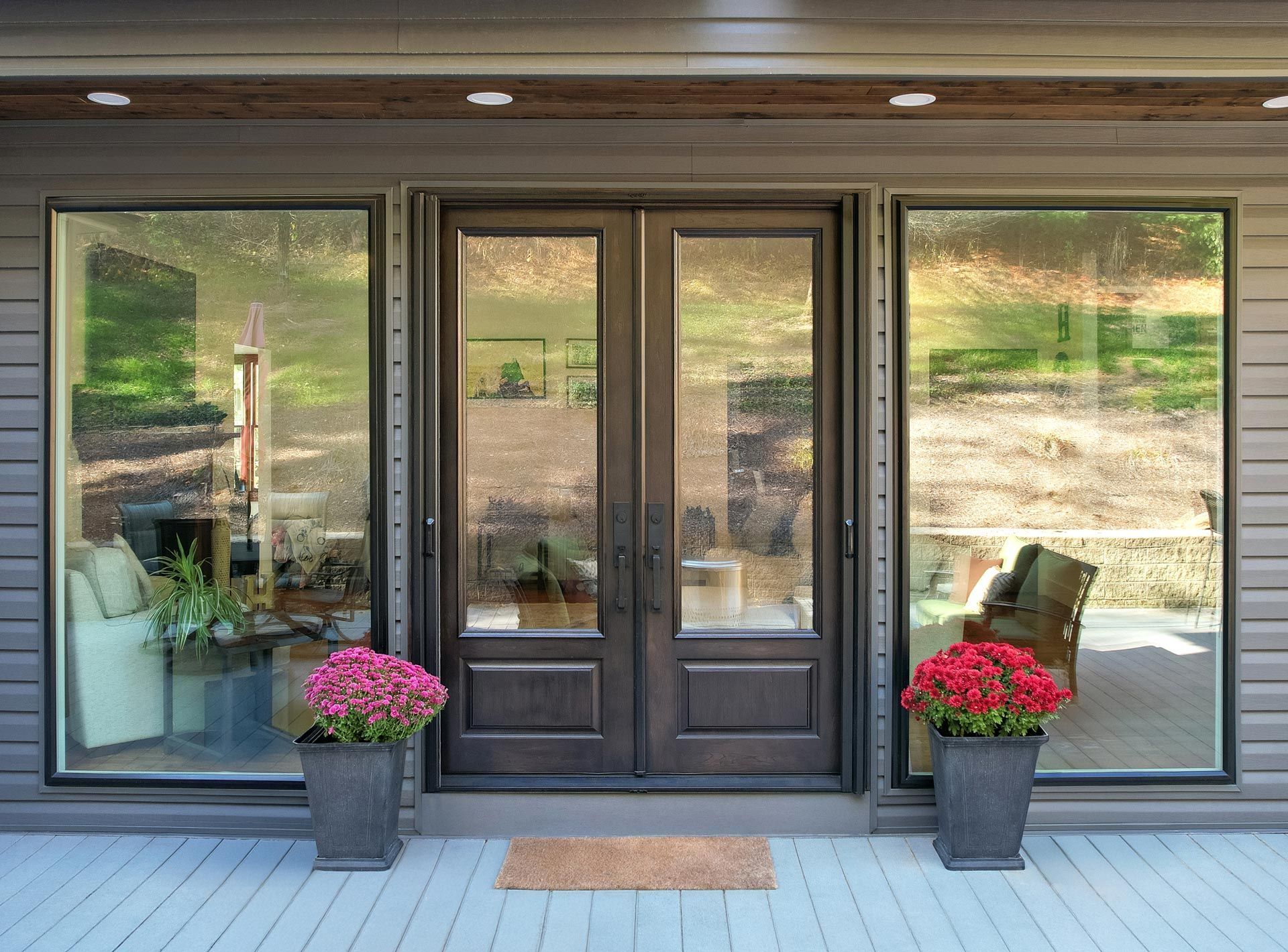 Front porch with dark double doors, large windows, and pink flower planters on either side