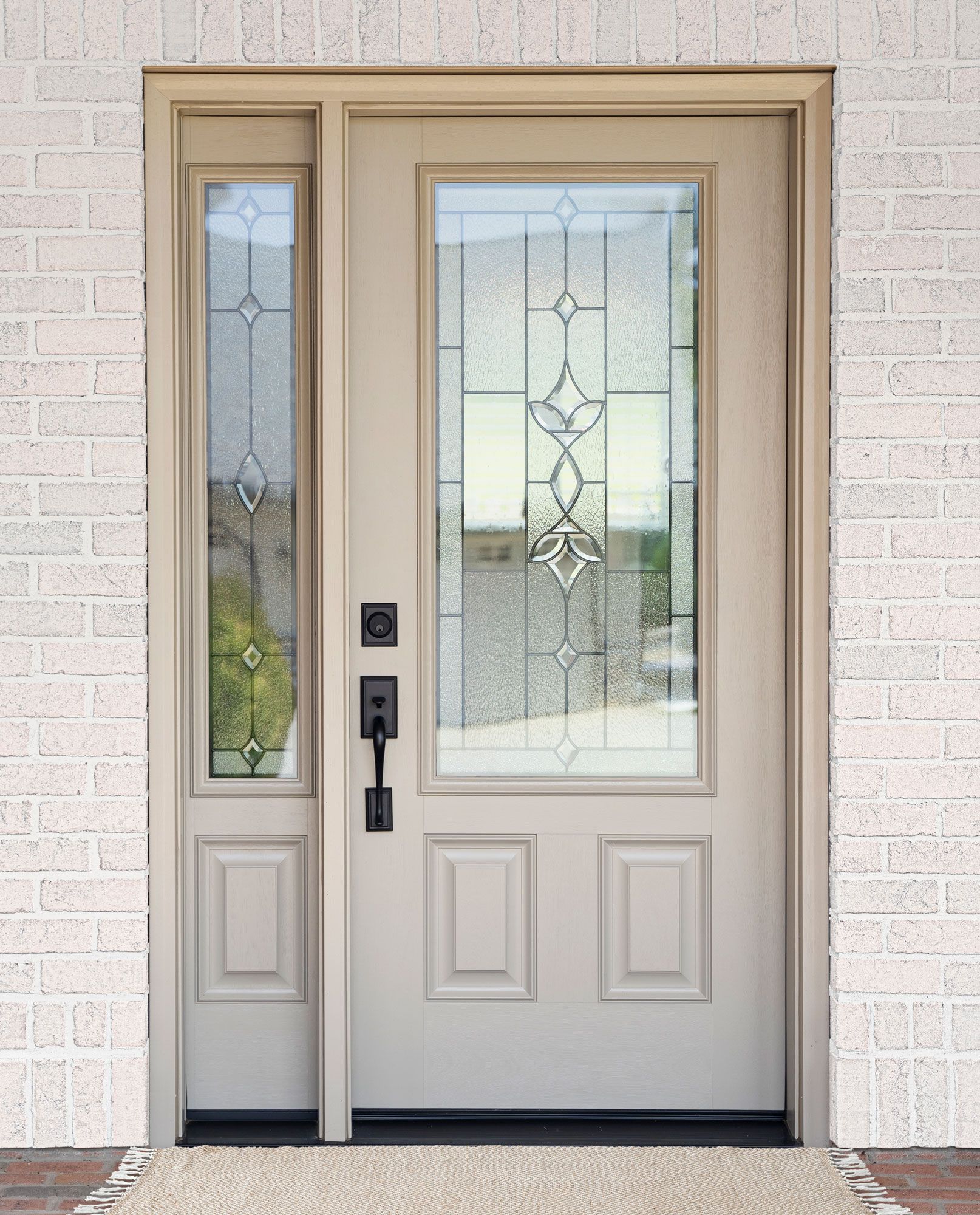 Beige double front door with frosted glass panels set in a white brick exterior wall