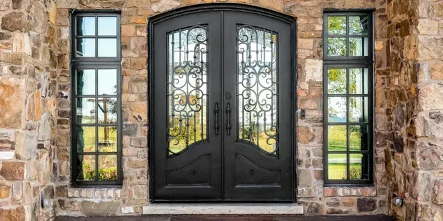 Front door with tall glass sidelights, wooden door marked “Welcome,” and potted topiary by the entrance
