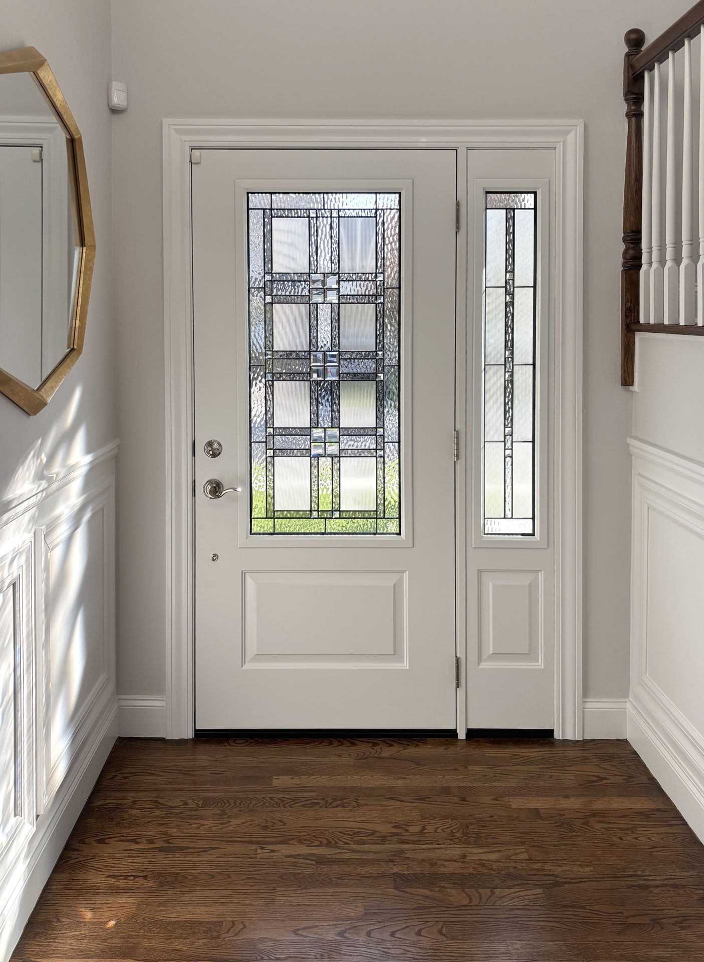 Front entry with white door, stained-glass window, sidelights, and dark wood floor