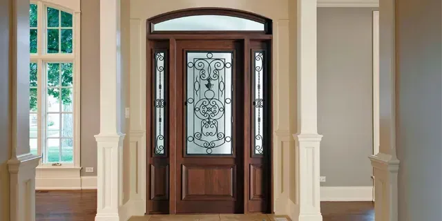 Interior entryway with wood front door, glass sidelights, and arched transom in a bright home