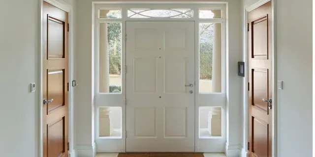 Bright entryway with a white front door, sidelights, and wooden closet doors on both sides