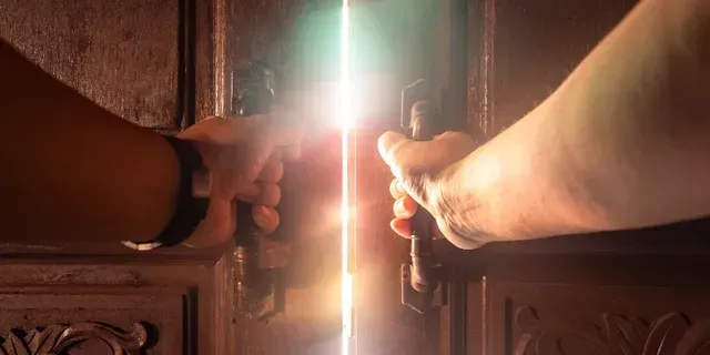 Hands opening a wooden door, with bright sunlight streaming through the gap